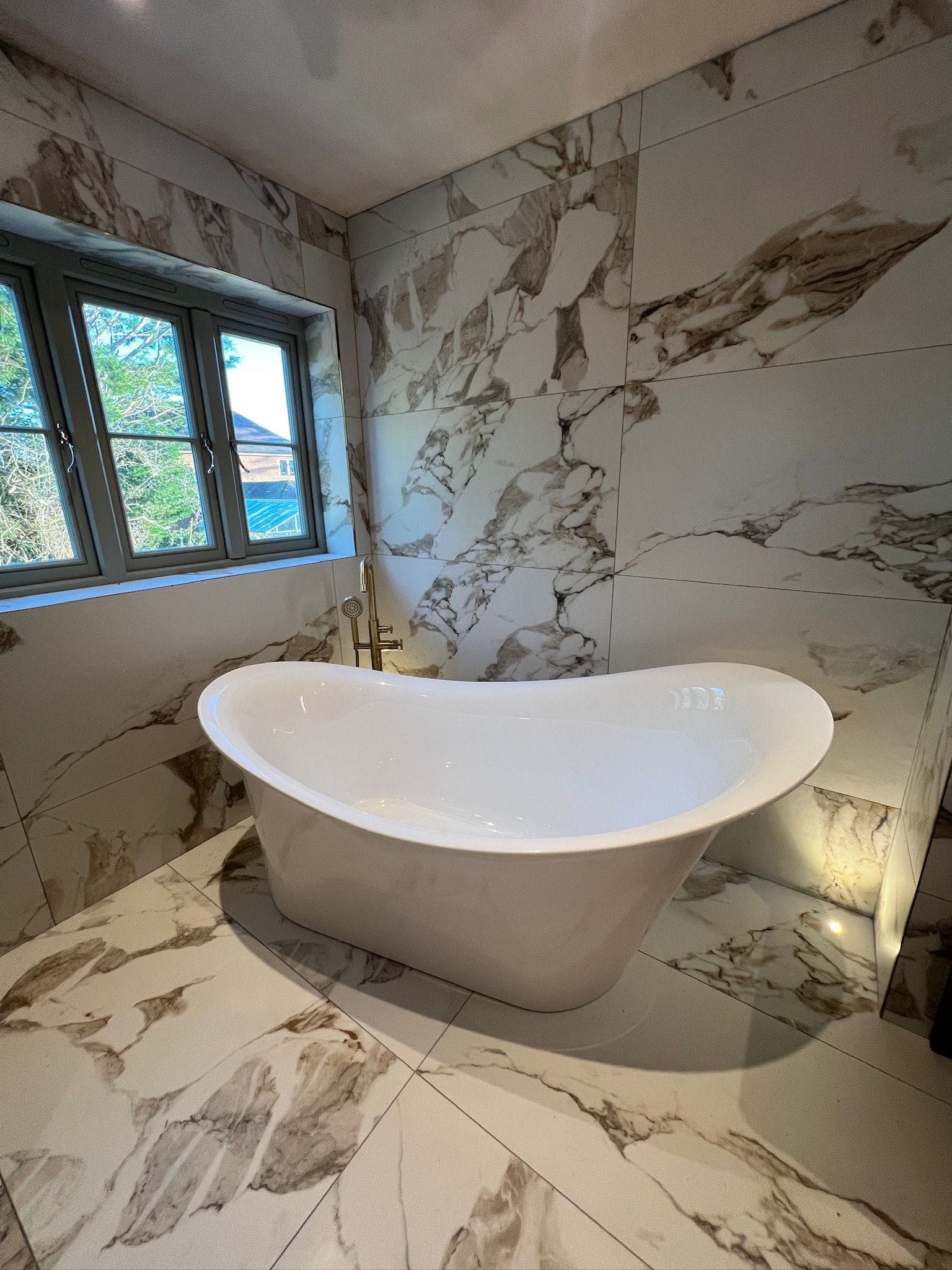 Luxury marble bathroom with freestanding bathtub and gold fixtures
