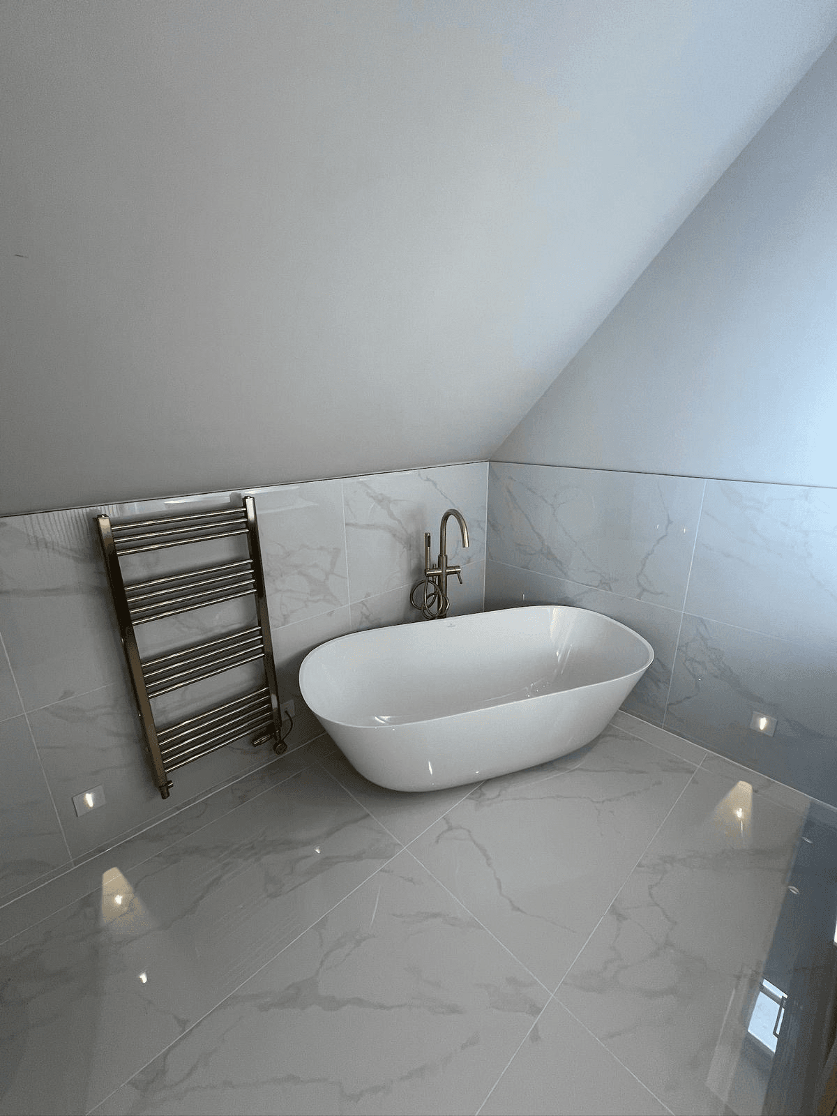 Attic bathroom with marble tiles and brass fixtures