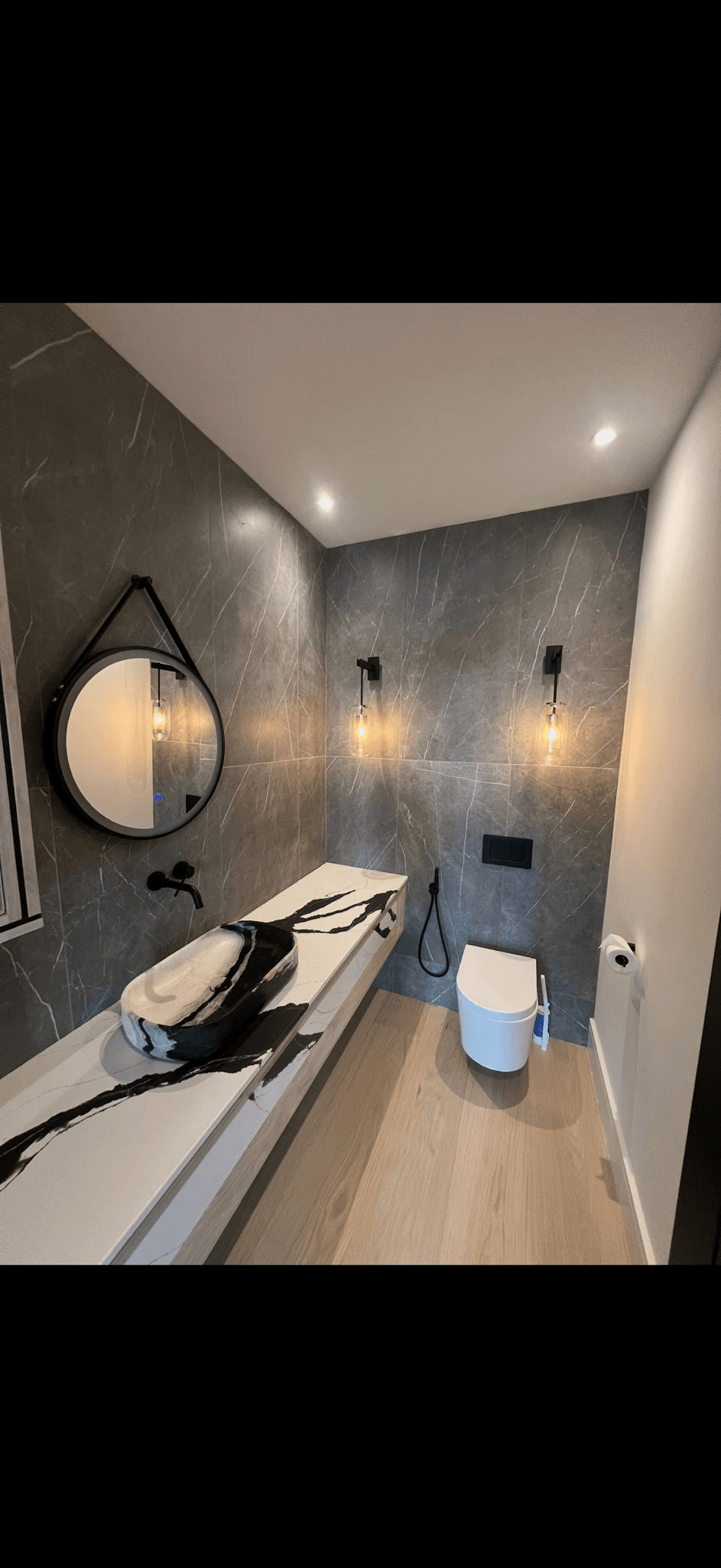 Modern dark bathroom with grey marble tiles and designer sink