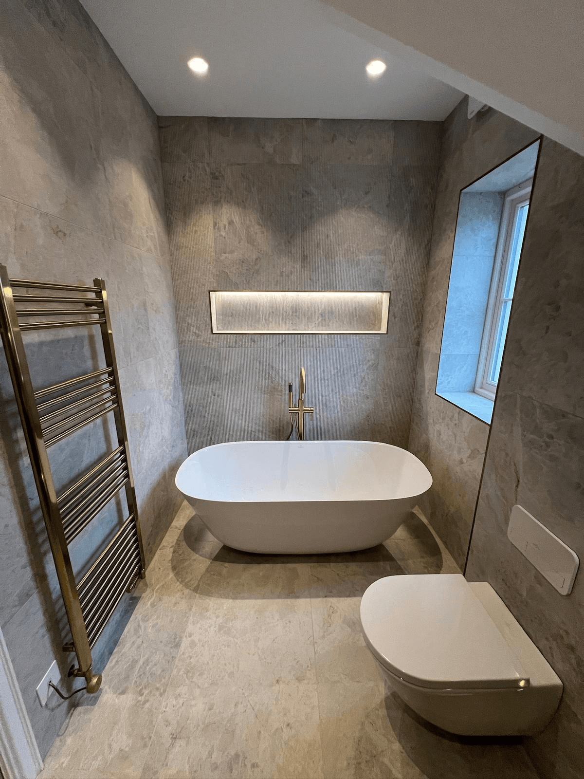 Modern grey stone bathroom with freestanding tub and heated towel rail