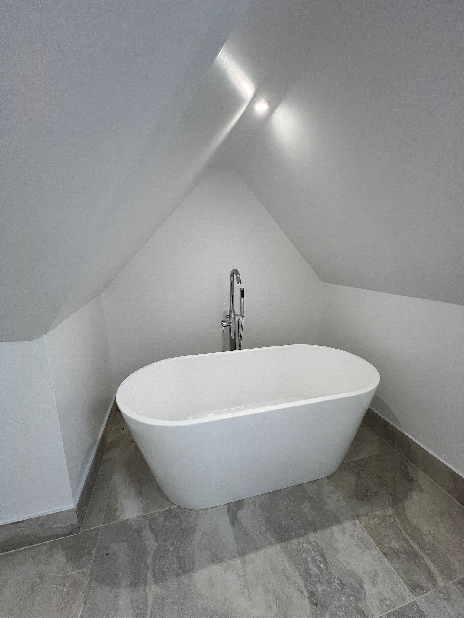 Minimalist attic bathroom with freestanding white tub